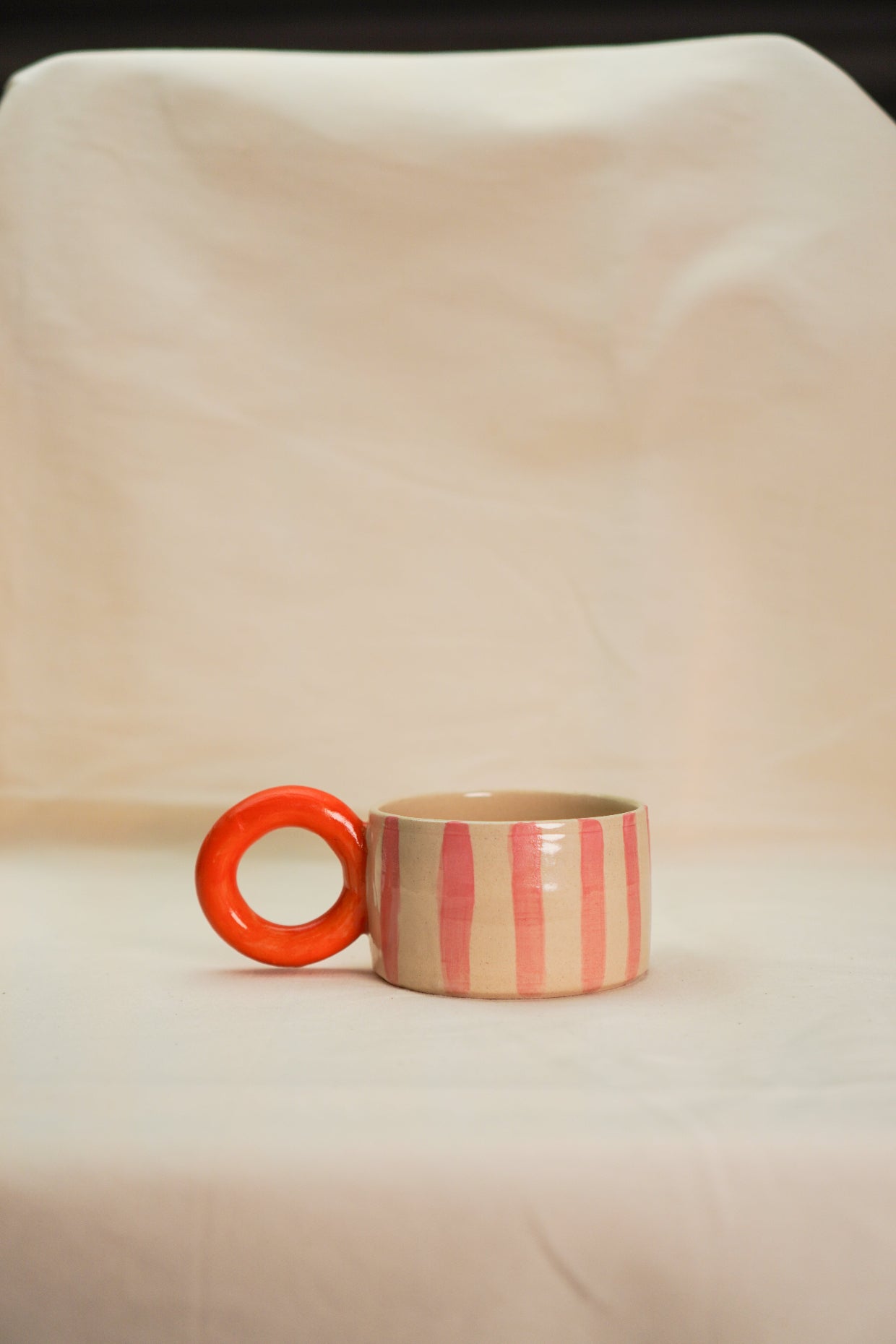 Filiżanka circus w paski różowe z okrągłym pomarańczowym uchem.